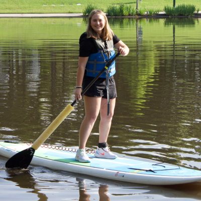 a little girl standing next to a body of water