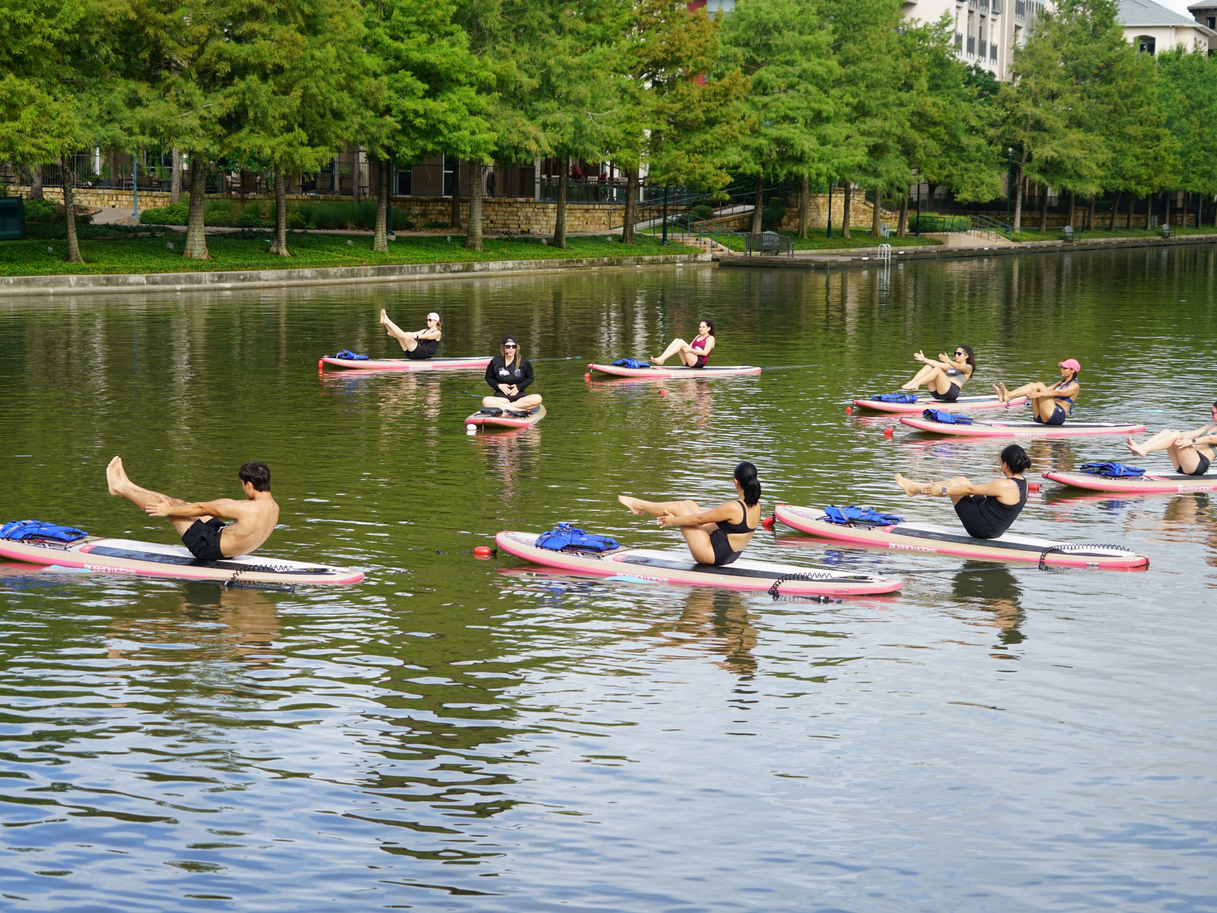 People practicing yoga on paddleboards in a calm river.