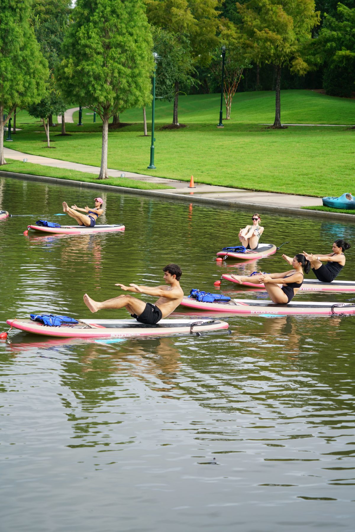 People doing yoga on paddleboards in a calm lake surrounded by greenery.
